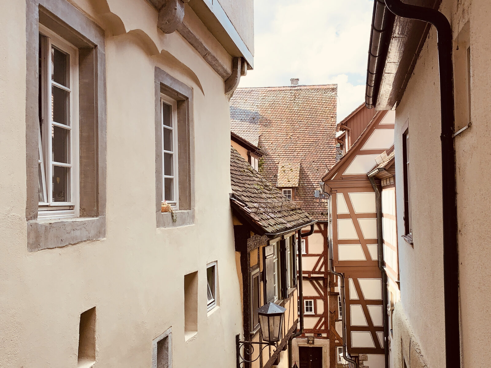 Eine enge Gasse in einer Altstadt mit Fachwerkhäusern. Die Gebäude sind dicht aneinander gebaut und strahlen historischen Charme aus. Ein paar Fenster und Türen sind sichtbar.