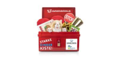 Eine rote Metallkiste mit der Aufschrift „Starke Kinder Kiste!“ gefüllt mit verschiedenen Materialien zur Gewaltprävention für Kinder. Zu sehen sind unter anderem ein Stofftier, ein Stoppschild, ein goldener Pokal und ein Buch mit dem Titel „Echte Schätze!“. Die Kiste ist ein Projekt der Deutschen Kinderschutzstiftung Hänsel + Gretel und des Petze-Instituts für Gewaltprävention.