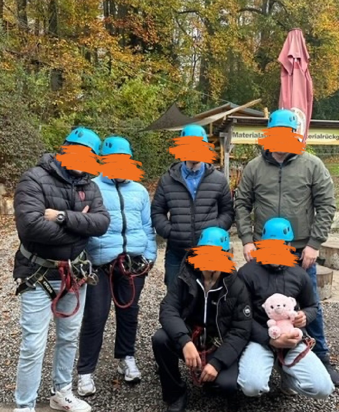 Eine Gruppe von sechs Personen in Outdoor-Kleidung und Helmen steht und sitzt auf einem kiesigen Untergrund. Ihre Gesichter sind unkenntlich gemacht.