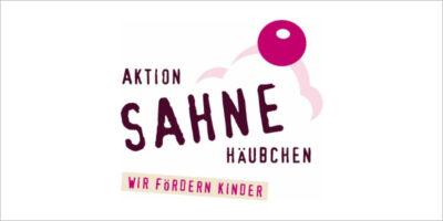 Das Bild zeigt das Logo der "Aktion Sahnehäubchen" mit dem Slogan "Wir fördern Kinder". Der Schriftzug ist in einer verspielten, handgeschriebenen Schriftart gehalten und wird von einer stilisierten Sahnehaube und einer Kirsche ergänzt. Die Farben des Logos sind hauptsächlich Rosa, Lila und Weiß.