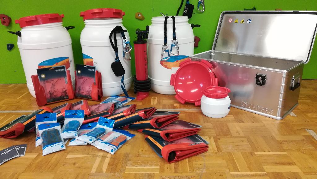 Eine Sammlung von verschiedenen Werkzeugen und Behältern liegt auf einem Tisch. Die Gegenstände sind ordentlich angeordnet und scheinen für handwerkliche Arbeiten bestimmt zu sein.