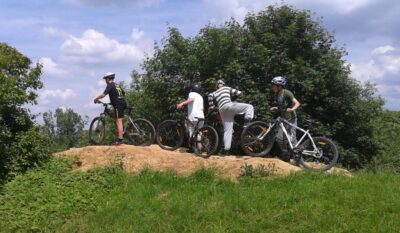 Eine Gruppe von Radfahrern steht mit ihren Fahrrädern auf einer Wiese und scheint eine Pause zu machen. Sie genießen die frische Luft und die Natur.