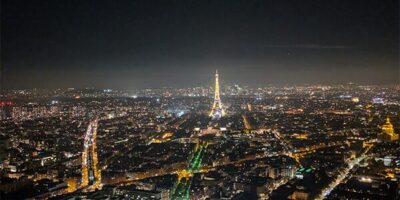 Das Bild zeigt einen Blick von oben auf die Stadt Paris bei Nacht. Alles leuchtet schön und auch der Eifelturm ist in der Ferne zu erkennen.